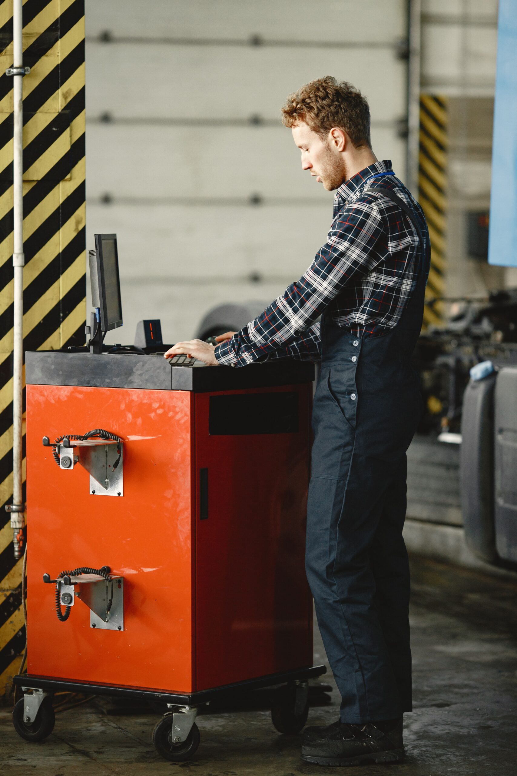 Auto mechanic using diagnostic equipment in a modern workshop environment.